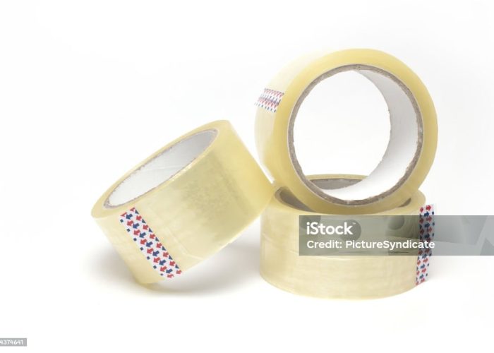 Close up of three rolls of transparent package adhesive tape stacked on top of each other and side by side on white background